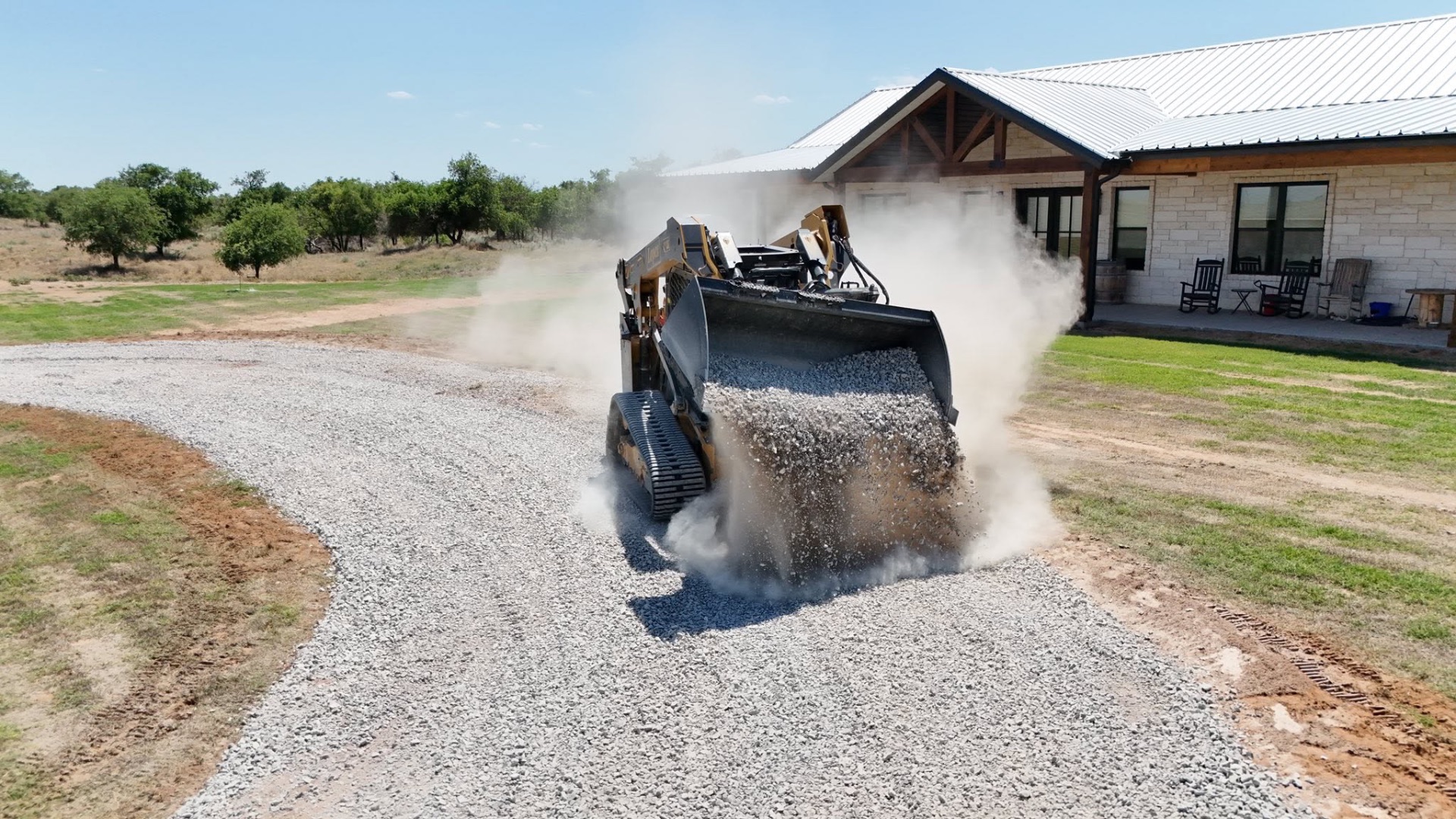 Skid steer spreading gravel on a rural driveway